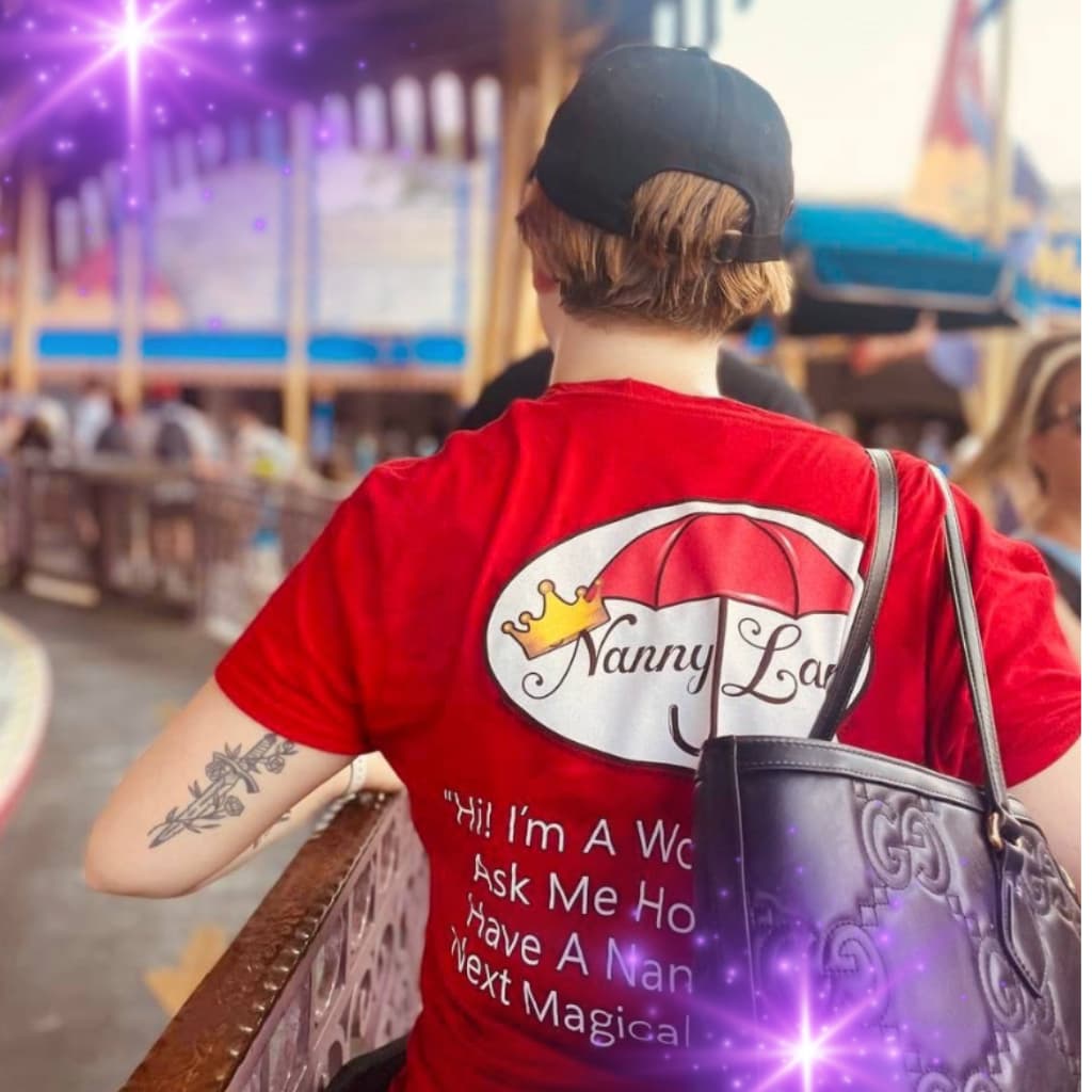 "Person in a red 'Nanny Lane' T-shirt with a logo and text on the back, carrying a black bag, with purple sparkles in the background."